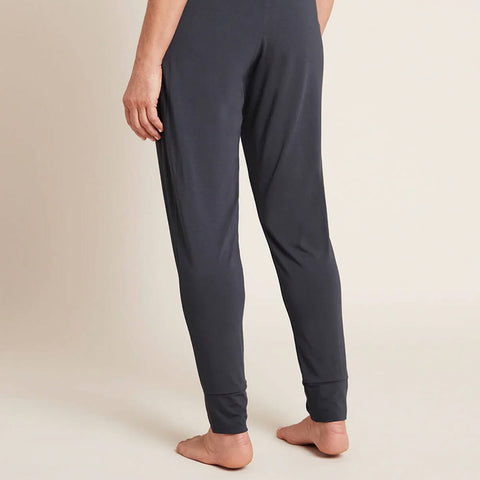 A model wearing navy blue, lightweight lounge pants made of organic bamboo, featuring a draped fit with a wide waistband, tapered leg and two side pockets, showing the back.