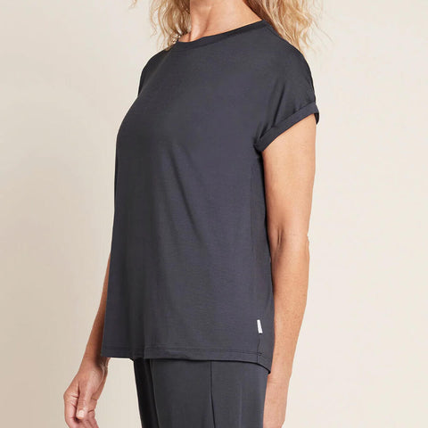 A model wearing a navy blue, lightweight lounge top made of organic bamboo, featuring a softly curved neckline, back seam detail and a subtle curved high-to-low-hem, showing the front.