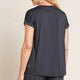 A model wearing a navy blue, lightweight lounge top made of organic bamboo, featuring a softly curved neckline, back seam detail and a subtle curved high-to-low-hem, showing the back.