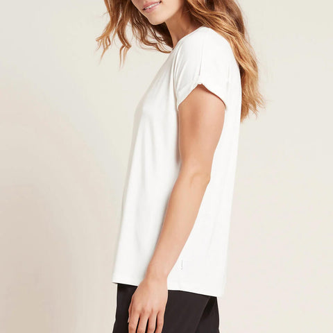 A model wearing a white, lightweight lounge top made of organic bamboo, featuring a softly curved neckline, back seam detail and a subtle curved high-to-low-hem, showing the side.