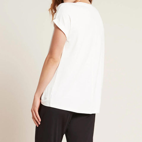 A model wearing a white, lightweight lounge top made of organic bamboo, featuring a softly curved neckline, back seam detail and a subtle curved high-to-low-hem, showing the back.