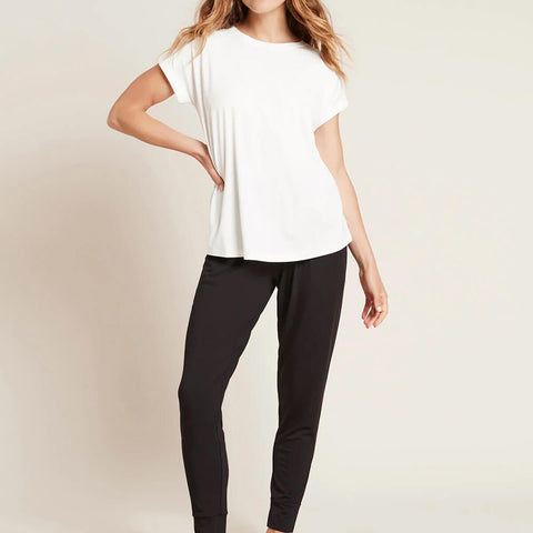 A model wearing a white, lightweight lounge top made of organic bamboo, featuring a softly curved neckline, back seam detail and a subtle curved high-to-low-hem, showing the front.