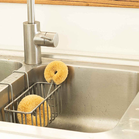 Plastic free, coconut fibre dish brush in a kitchen sink.