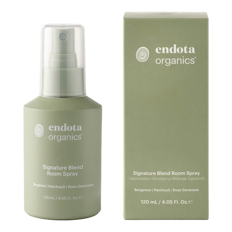 A 120ml bottle of endota Signature Blend Room Spray placed next to its matching box. The bottle is shown with its elegant label facing forward, while the box features complementary design elements and text. The box includes product information and branding details that align with the bottle’s sleek, minimalist aesthetic. Both the bottle and box are set against a white background to highlight their refined design and packaging.