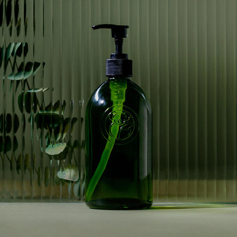 Green apothecary glass bottle with a pump dispenser styled.