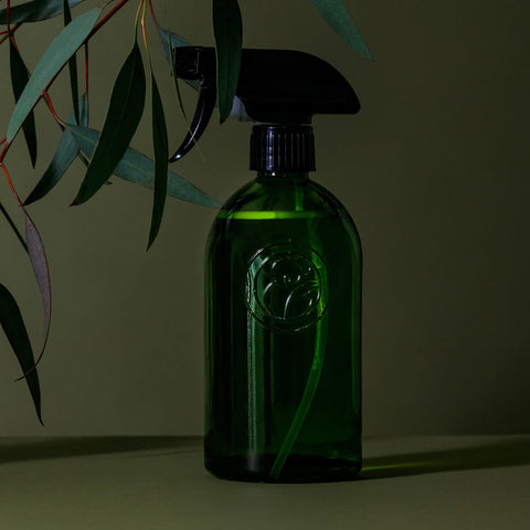 Green apothecary glass bottle with a spray trigger styled.