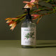 Plastic pump bottle of rosalina and peppermint natural body wash styled with leaves on a surface.