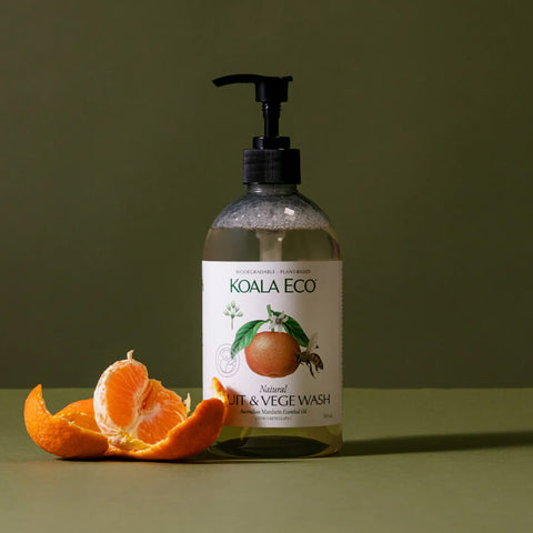 Plastic pump bottle of natural fruit and vege wash styled with a mandarin on a surface.