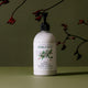 Plastic pump bottle of rosalina and peppermint natural hand and body lotion styled with plants on a surface.