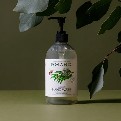 Plastic pump bottle of lemon scented eucalyptus and rosemary hand wash styled with leaves on a surface.