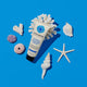 100ml bottle of Little Urchin Natural Clear Zinc Sunscreen SPF 50+ on a blue surface with coral and seashells scattered around the scene. The sunscreen is a hydrating, vegan formula that provides UVA and UVN broad spectrum protection from the sun while also being 4 hours water-resistant. Packaged in a cream tube with minimal blue and black text on the label.