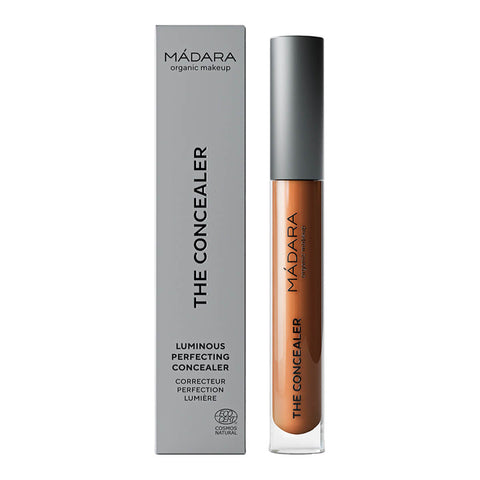 Madara The Concealer in shade Mocha #65, a naturally certified concealer that hides dark circles, blemishes, and redness with a dewy finish. It offers long-lasting comfort and contains hydrating hyaluronic acid and retouching minerals. Packaged in a slim, cylindrical tube with a twist-off cap and a built-in applicator, featuring the brand name on the label.