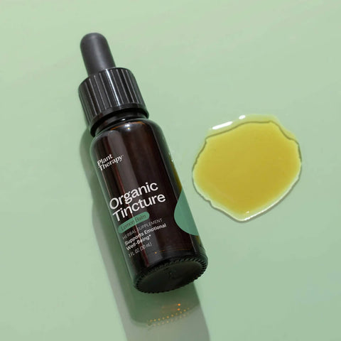 Dropper bottle of lemon balm organic herbal supplement styled on a surface with drops of the product next to it.