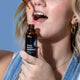 Person holding dropper bottle of an organic herbal supplement for sleep and putting drops in mouth.