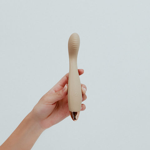 Hand holding Viola Green Hedon G-Spot Vibrator in Ivory colour, designed for reaching all the hard-to-reach spots. Its curvy body features elegant contours, and a ribbed shaft designed to maximise your most intense G-spot orgasms. It's crafted from sustainable materials and has a rechargeable lithium power supply with magnetic charging port. Hedon offers guilt-free exploration and companionship in your sexual wellness practices.