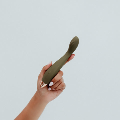 Hand holding Viola Green Hedon G-Spot Vibrator in Olive colour, designed for reaching all the hard-to-reach spots. Its curvy body features elegant contours, and a ribbed shaft designed to maximise your most intense G-spot orgasms. It's crafted from sustainable materials and has a rechargeable lithium power supply with magnetic charging port. Hedon offers guilt-free exploration and companionship in your sexual wellness practices.