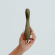 Hand holding Viola Green Hedon G-Spot Vibrator in Olive colour, designed for reaching all the hard-to-reach spots. Its curvy body features elegant contours, and a ribbed shaft designed to maximise your most intense G-spot orgasms. It's crafted from sustainable materials and has a rechargeable lithium power supply with magnetic charging port. Hedon offers guilt-free exploration and companionship in your sexual wellness practices.