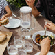 2L waterdrop Lucy Filter Carafe water filtering jug styled on a table with glasses and food. The jug is made of robust, odourless and tasteless borosilicate glass, and features a minimal and sleek design.