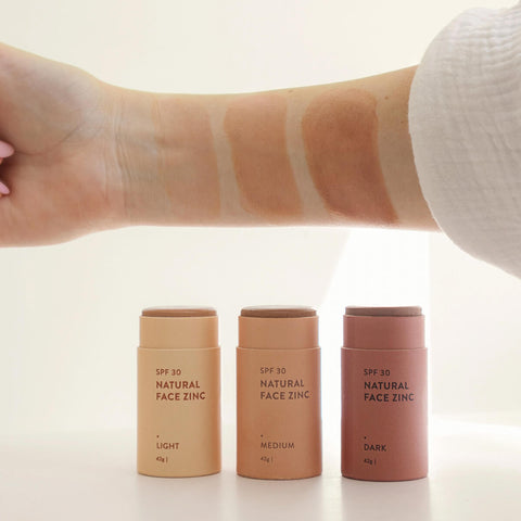 Winki Zinc Tinted Face Zinc shades (Light. Medium, Dark) swatched on an arm. A lightweight, everyday-wear formula with SPF 30 that offers light, glowy coverage. Packaged in a compostable and recyclable cardboard tube.