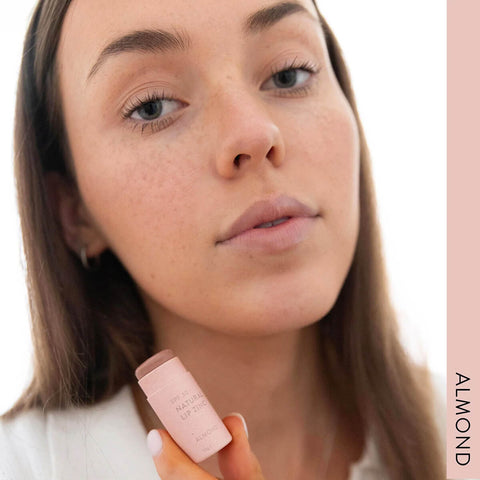 Model wearing Winki Zinc's Tinted Lip Zinc in the shade, Almond, a very subtle, light neutral colour. Perfect for a “nude” look or as a highlighter (light pigment). Tinted Lip Zinc is a mineral-based lip balm designed to heal and protect your lips from the sun while adding a hint of natural colour.