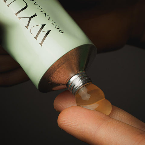 Tube of vegan cleansing balm squeezing product out onto fingers.